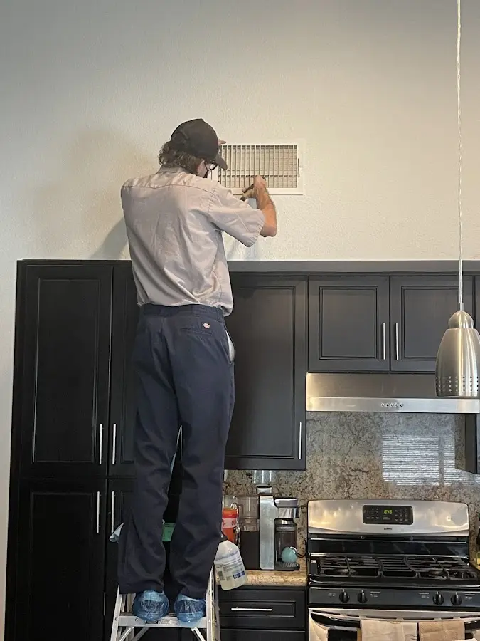 Technician inspecting an air vent during HVAC service in Los Fresnos